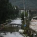 Downed powerlines hang over a buckled road next to high waters following flooding after heavy rains at Xin'anzhuang village, in Miyun district, on the outskirts of Beijing on July 28, 2025. (Photo by Jade GAO / AFP)