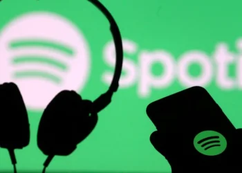 A smartphone and a headset are seen in front of a screen projection of Spotify logo, in this picture illustration taken April 1, 2018.