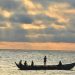 A silhouette of fishermen on a canoe at sunset.